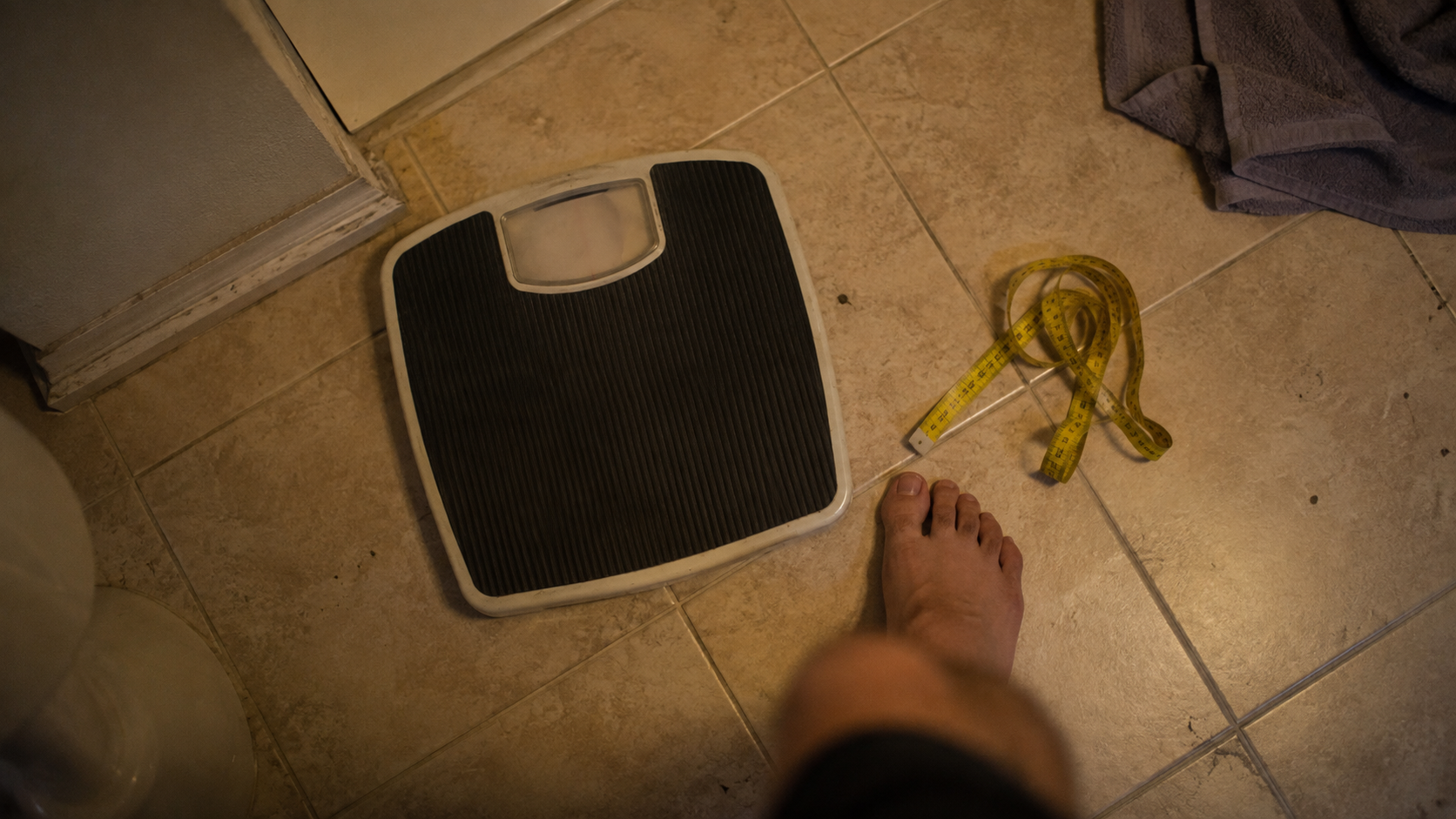 calculate body fat with height and weight — bathroom scale and measuring tape on a bathroom floor